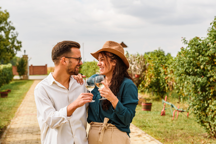 Couple toasting wine glasses in the vineyard