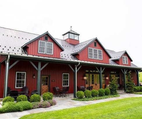 The red barn-style tasting room at Williams Gap Vineyard with a covered porch, patio seating and green lawn