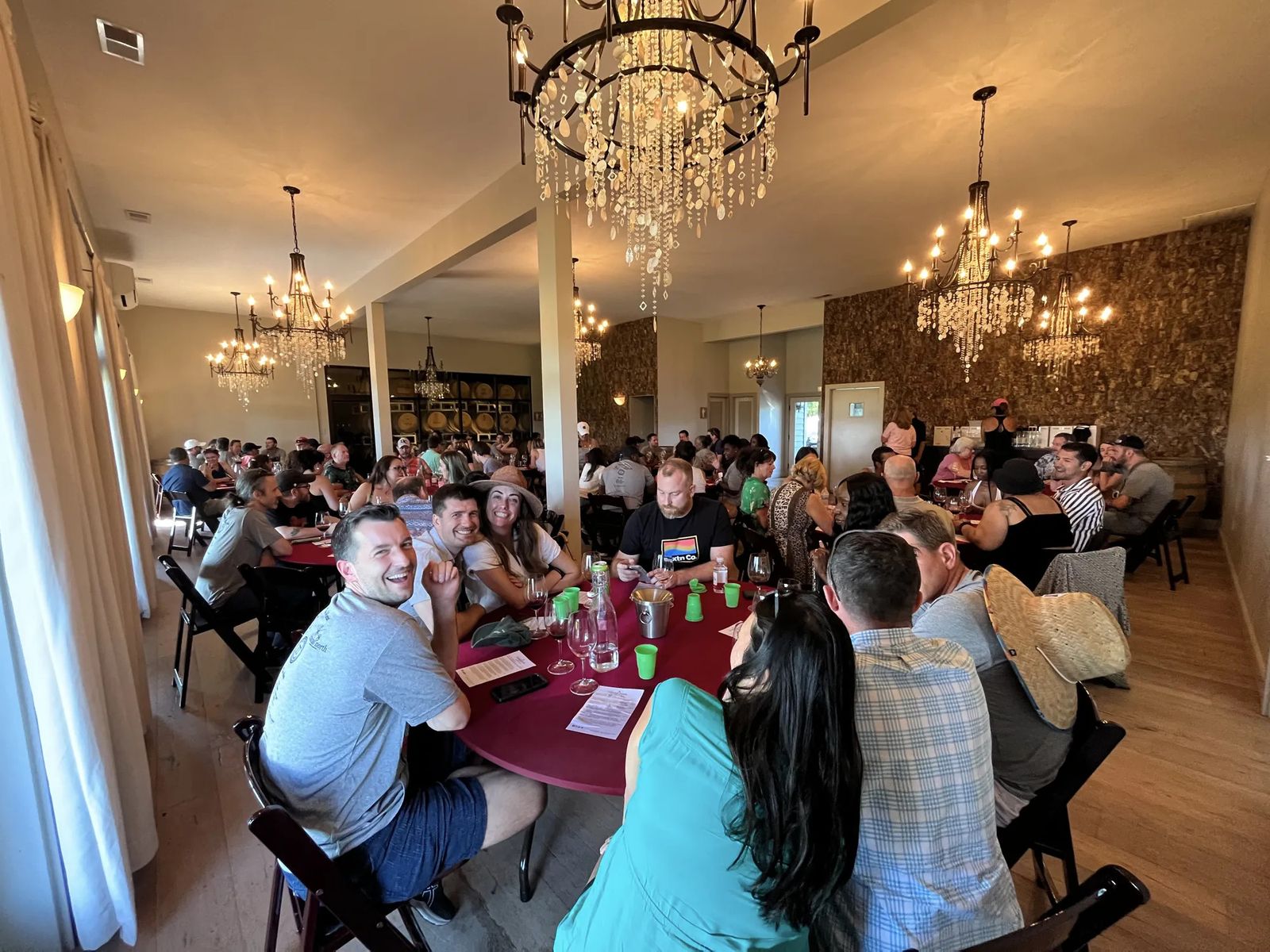 Guests seated around tasting tables in a room lit by chandeliers