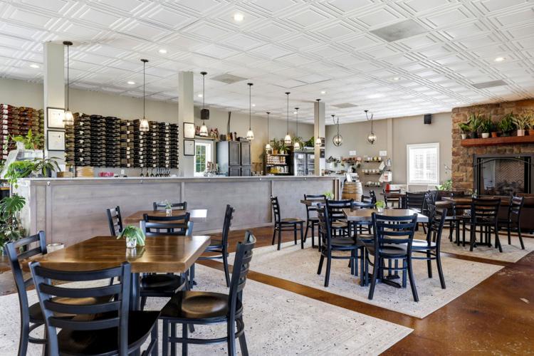 The 8 Chains North tasting room with a long bar, wine racks, pendant lights and a stone fireplace