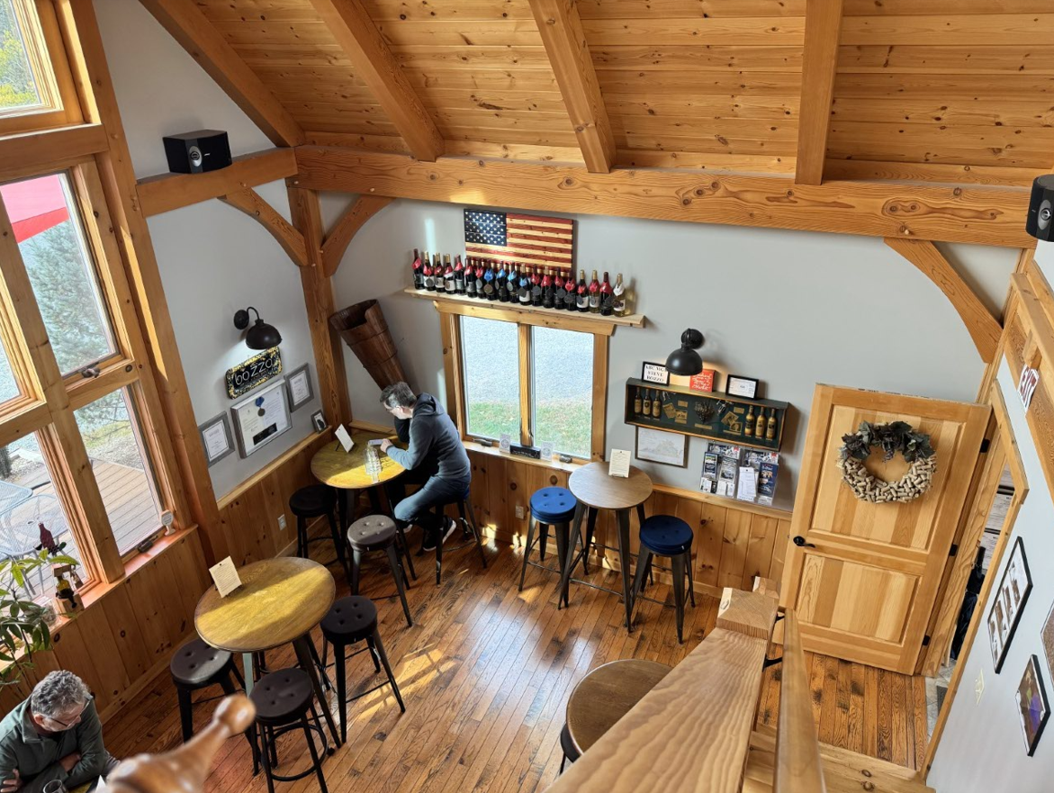 Bozzo Family Vineyards tasting room with timber beams, high-top tables and a shelf of wine bottles