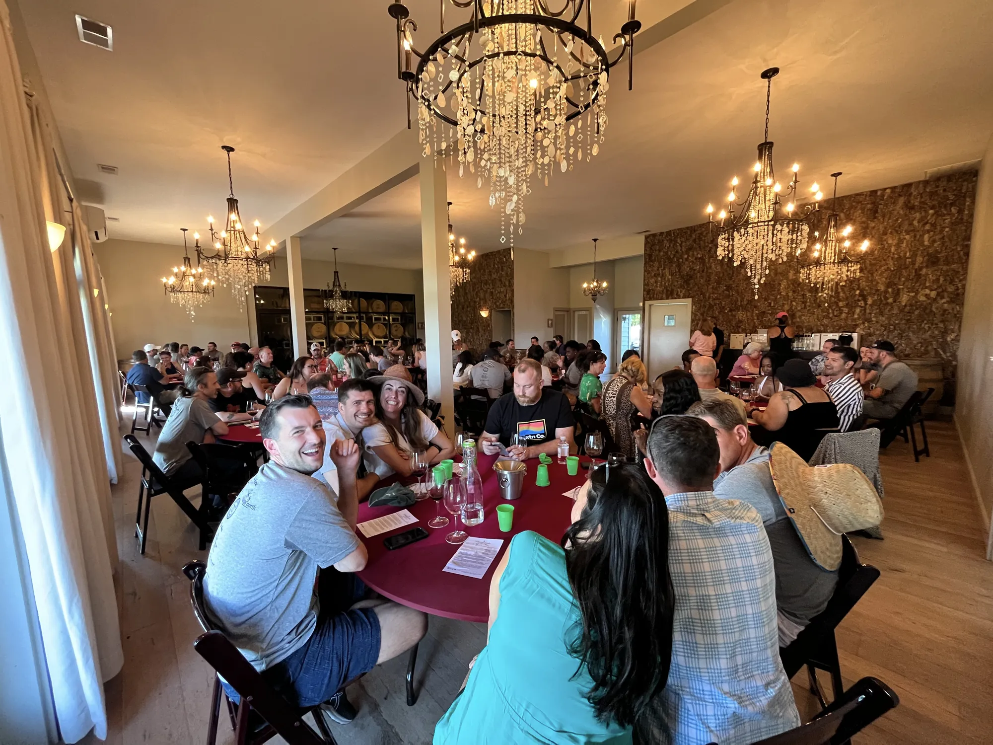 A lively room of guests at tables under chandeliers